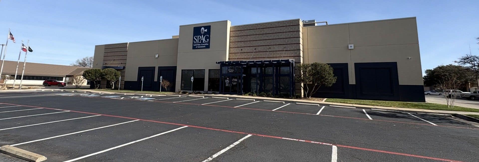 The SPAG office in Lubbock: a tan and brown building with the navy SPAG sign above its entrance, flags out front