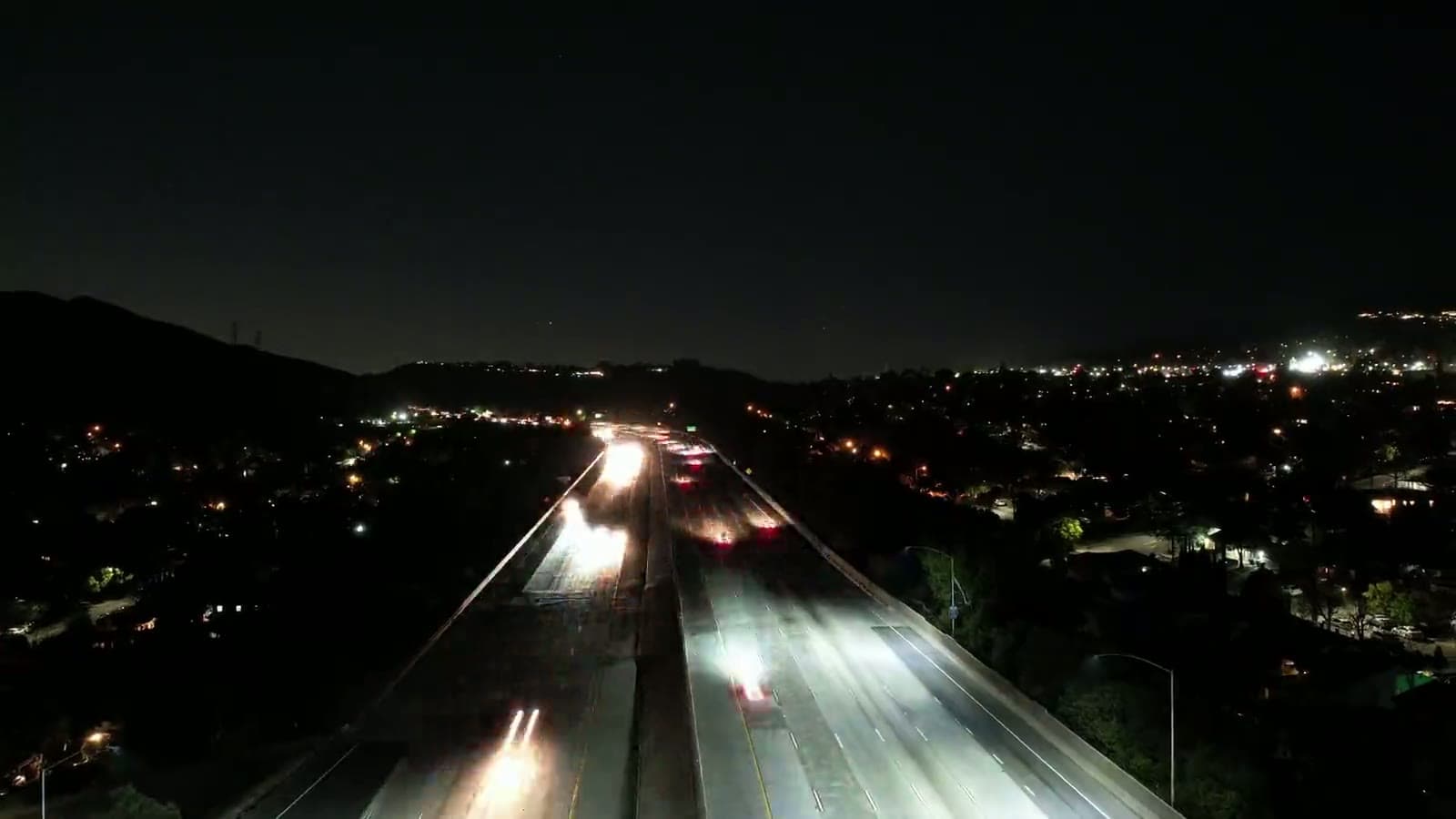 Traffic streaming along a highway at night, seen from above
